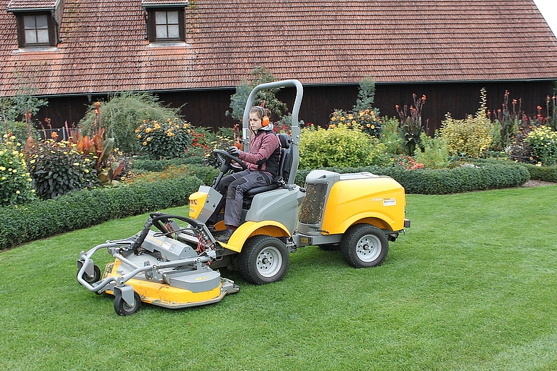 Junge Frau auf Aufsitzrasenmäher in den Gärten des Lehr- und Versuchshofs Tachenhausen