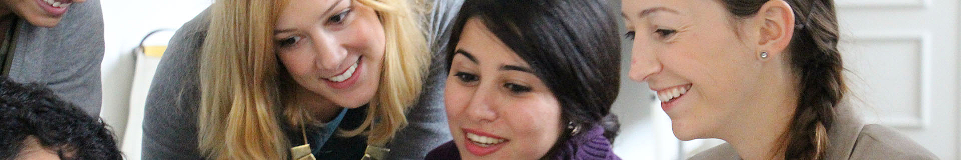 Das Bild zeigt eine Gruppe von Personen, deren Gesichter unscharf dargestellt sind. Sie befinden sich nah beieinander, was auf eine gemeinschaftliche oder soziale Aktivität hindeutet.