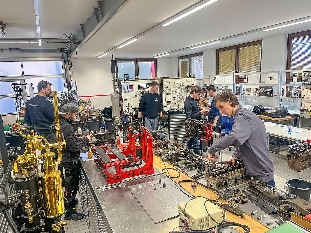 Metallwerkstatt mit mehreren Personen an Arbeitstischen