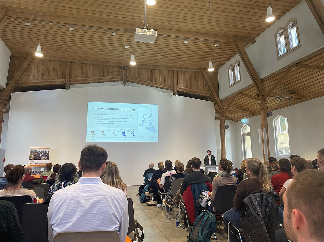 Zuhörer im Saal beim Vortrag mit Prof. Röhl am Rednerpult